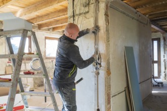 A worker installs cables on a construction site