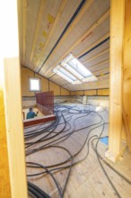 An attic under construction with wood paneling and cables
