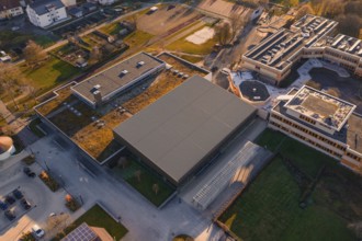 Aerial view of a modern building complex with green spaces and sun in the background, Althengstett