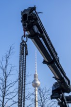 Crane boom with steel chains obscures view of the TV tower on Alexanderplatz, Berlin, Germany
