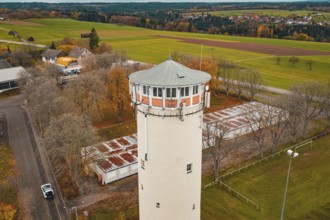 Water tower in rural autumn landscape with trees and small buildings in the village, water tower,