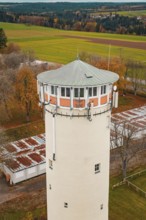 Close-up of the upper part of a water tower with green roof surrounded by autumn trees, Wasserturm,