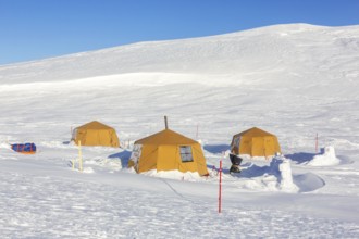 Arctic expedition camp with tents in the snow, protected by tripwire polar bear alarm fence at