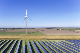 Aerial view over hybrid power plant combing solar photovoltaic modules and wind turbines, North
