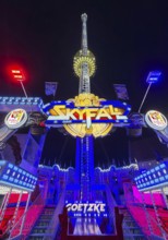 Colourfully illuminated Skyfal free fall tower at night at the All Saints Fair, Soest, North