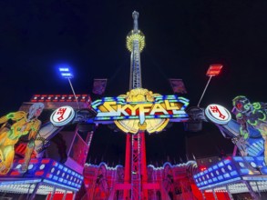 Colourfully illuminated Skyfal free fall tower at night at the All Saints Fair, Soest, North