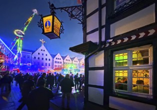 All Saints Fair in the evening with a half-timbered house and colorful illuminated rides, Old Town,