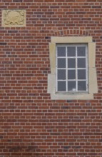 A rectangular window and a coat of arms in a red brick façade, Düstermühle, Münsterland, North