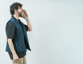 Casual young man in glasses shouting a promotion. Male person shouting an announcement isolated