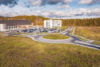 Building complex and roundabout in autumn landscape under blue sky, new Lindenrain industrial park,