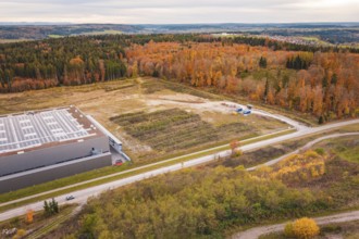 Landscape with road and autumn forests next to an industrial building, new Lindenrain industrial