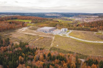 Hilly landscape in autumn with modern building and surrounding forest, new Lindenrain industrial