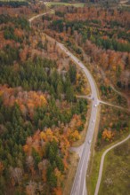 Winding country road through colorful autumn forest with occasional traffic, new Lindenrain