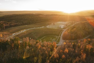 Sunset over a building in an autumn forest area with golden lighting, new Lindenrain industrial