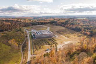 Aerial view of a building surrounded by an autumn forest landscape with dramatic sky, new
