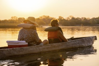 Sunset boat trip, tourists in a Mokoro, dugout boat on the Okavango River, Caprivi Strip, Namibia