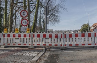 Road block with warning signs and yellow lights surrounded by bare trees in winter, Münsterland,