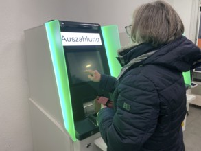 Elderly woman at an EC cash machine, operates screen, has money withdrawn, BW-Bank,