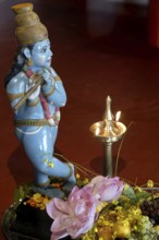 Sculpture of shepherd god Krishna playing his flute, fruits and vegetables lying on the ground,