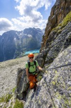 Mountaineer climbs on steep rock face in the secured via ferrata Crocodile Mountain Lake at