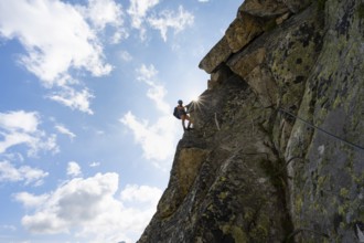 Female mountaineer on steep rock face on the secured via ferrata Krokodil-Bergsee am