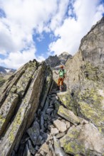 Mountaineers between boulders on the secured via ferrata Crocodile Mountain Lake at