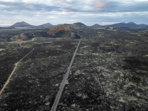 Road through lava fields, volcanic landscape with volcanic craters, Los Volcanes Natural Park,