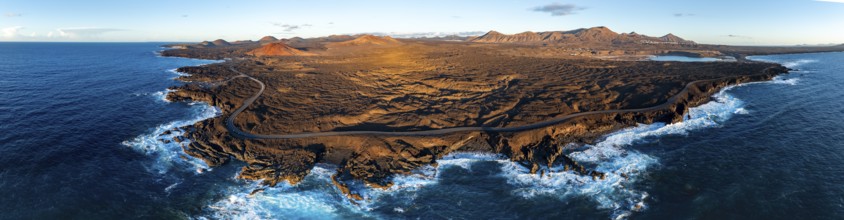 Coast with lava fields, volcanic landscape near Los Hervideros with red volcano Montaña Bermeja, in
