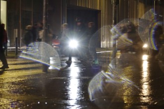 Passers-by in the evening in rainy weather in a city, November, Germany