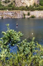 Tourist on a zip line across the lake, Opal Lake in the granite quarry, Moselleøkken