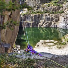 Ropes, slings and carabiners secured on a rock edge, opal lake in the granite quarry, Moselleøkken