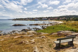 Reddish shimmering granite rocks, sandy bottom, wooden bench, Sandvig Strand, coastline,