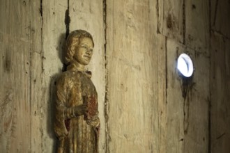 Carved wooden figure holding a book, Garmo Stave Church, Maihaugen open-air museum with houses and