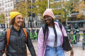 Diverse happy young adult friends are enjoying a cheerful walk together on a city street, smiling