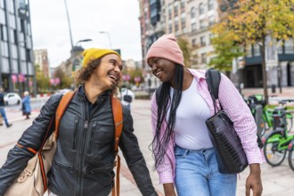 Happy young diverse couple walking together on a city street, sharing a joyful moment and laughing