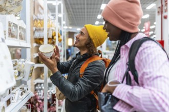 Young diverse couple browsing festive holiday decorations and gift ideas on department store