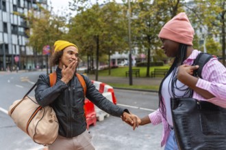 Young diverse couple holding hands while walking on an urban street, exploring the city together