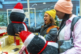 Young diverse couple excited discovering festive penguin decorations while shopping for holiday
