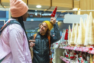 Diverse young couple laughing and shopping for festive holiday decorations in a bright store,