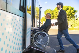 Young man assisting an elderly person using a wheelchair to board a public transport bus via an