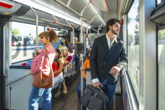 Passengers of diverse ages and ethnicities riding a city bus during a weekday commute, some sitting