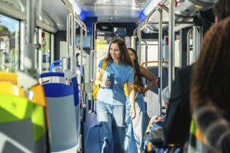 Young woman passenger holding a reusable coffee cup and backpack, walking through the aisle of a