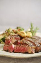 Juicy grilled steak medium rare on a white plate, with tender pink meat visible