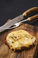 Tender pork chop topped with gooey melted cheese, served on a rustic wooden cutting board.