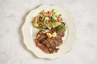 A delicious plate with perfectly grilled steak bone-in sliced into portions alongside a vibrant