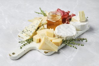 A beautiful spread featuring various types of cheese, honey in a jar, and slices of cured meat on a
