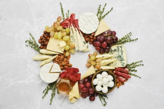 A colourful cheese and fruit platter displays a variety of cheeses, grapes, nuts, and cured meats,