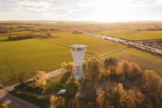 Water tower in autumn landscape with a wide view over fields and roads in the evening light,