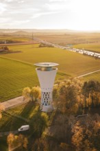 Water tower in autumn landscape surrounded by fields and trees at sunset, Möglingen water tower,