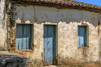 An old, abandoned house, ravaged by time, with its blue windows and crumbling plaster on the walls